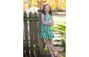 Model in ruffle sleeve twirly dress in greens market print