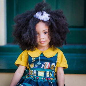 Girl wearing baby pinafore dress in Canning print over mustard collared shirt.  Unique toddler clothing for your tiny style icon.